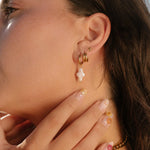 Close-up of a person wearing multiple gold hoop earrings with a blurred background