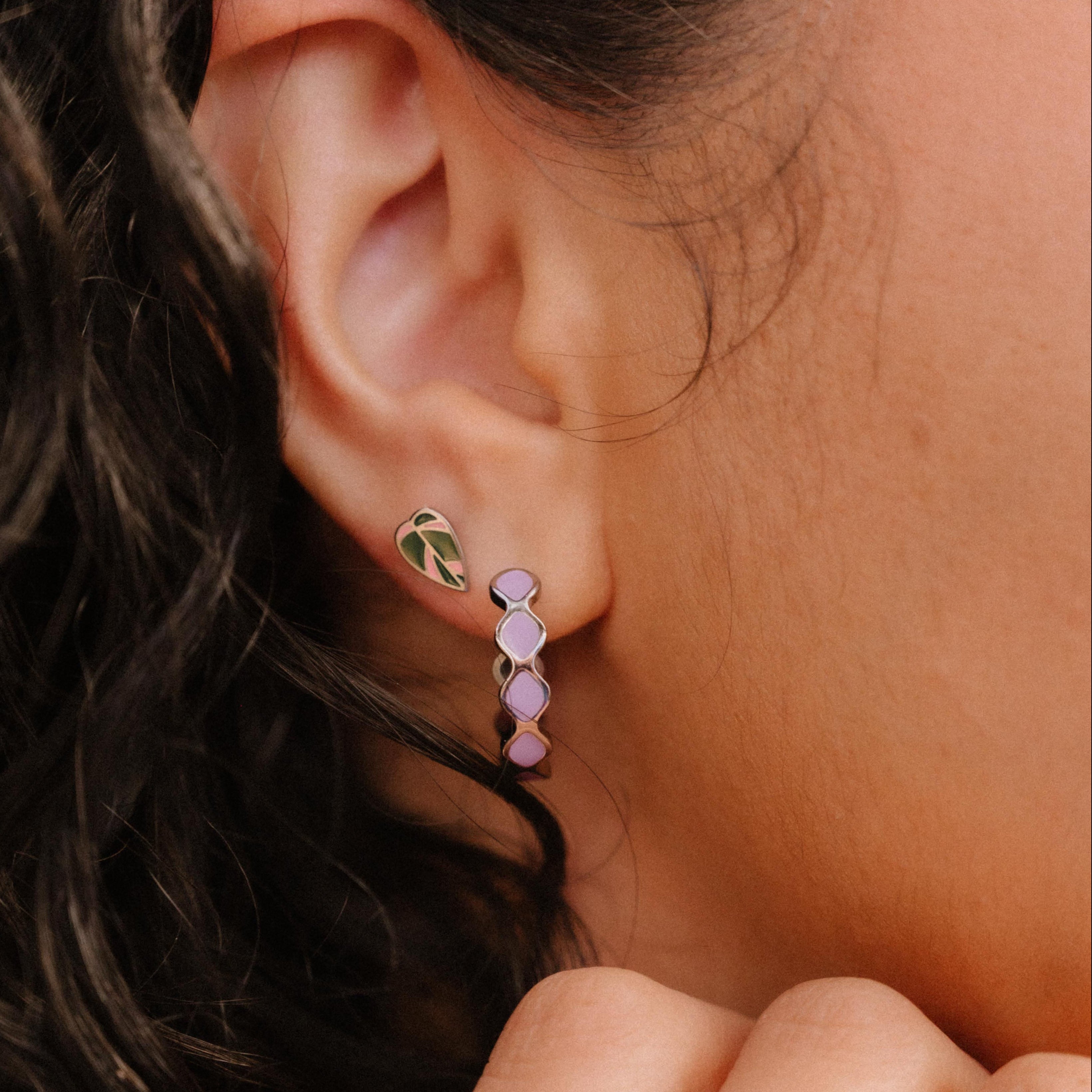 Close-up of an ear wearing a colorful earring with a blurred background