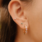 Close-up of a person wearing earrings with a blurred natural background