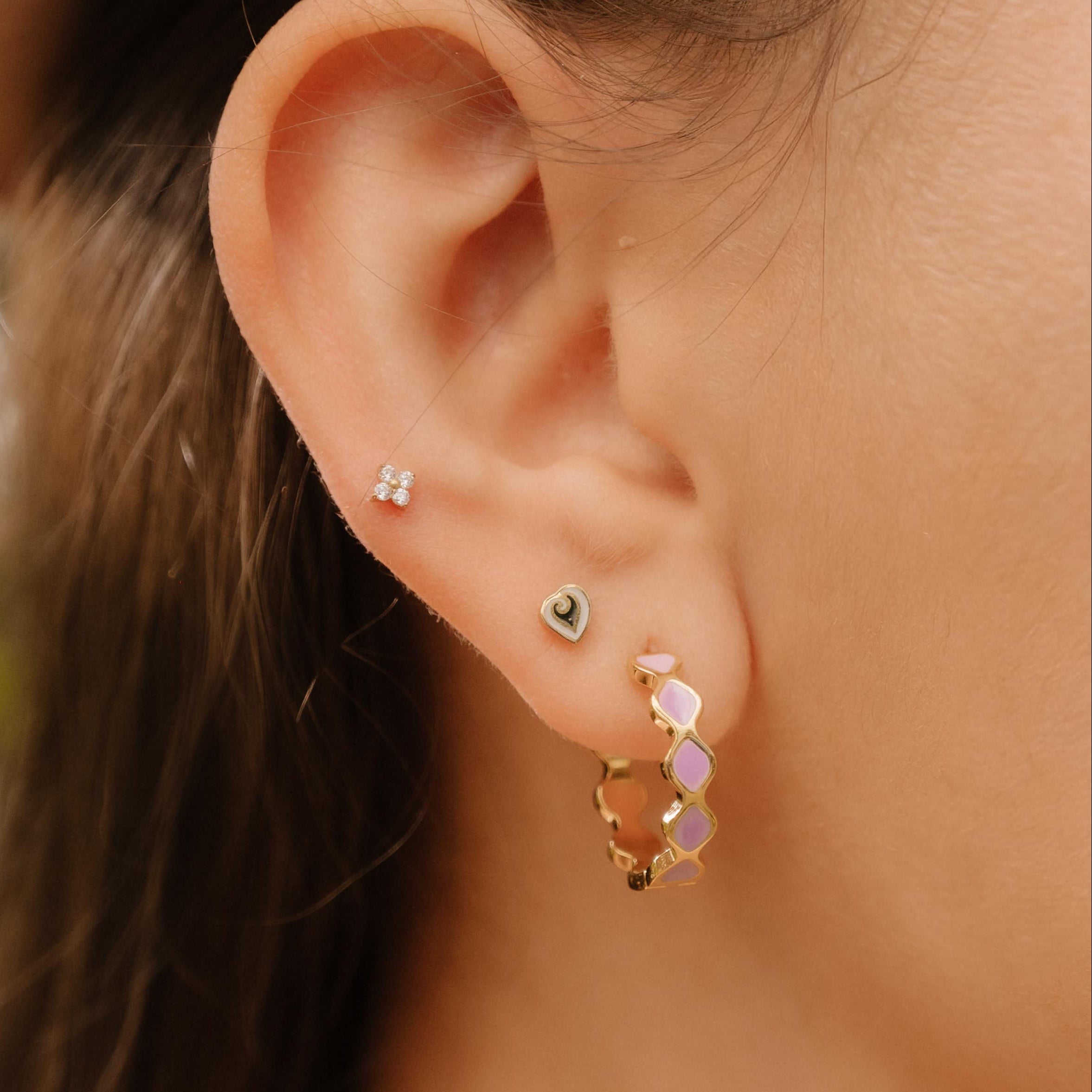 Close-up of a person wearing earrings with a blurred natural background