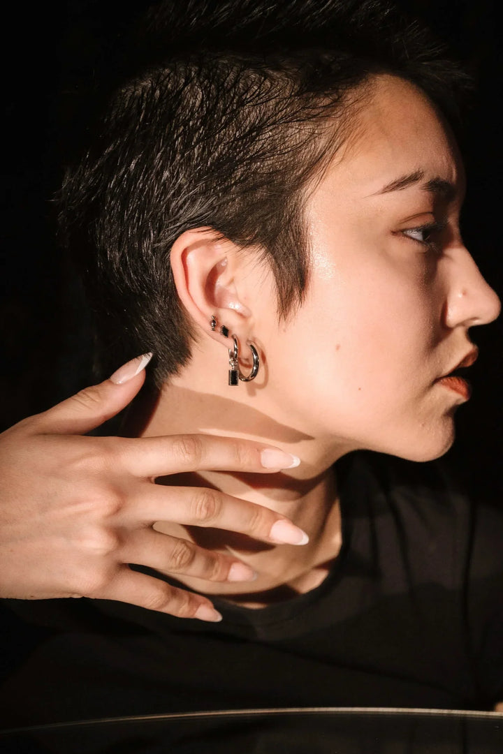 Side profile view of model showing of silver and black earring stack