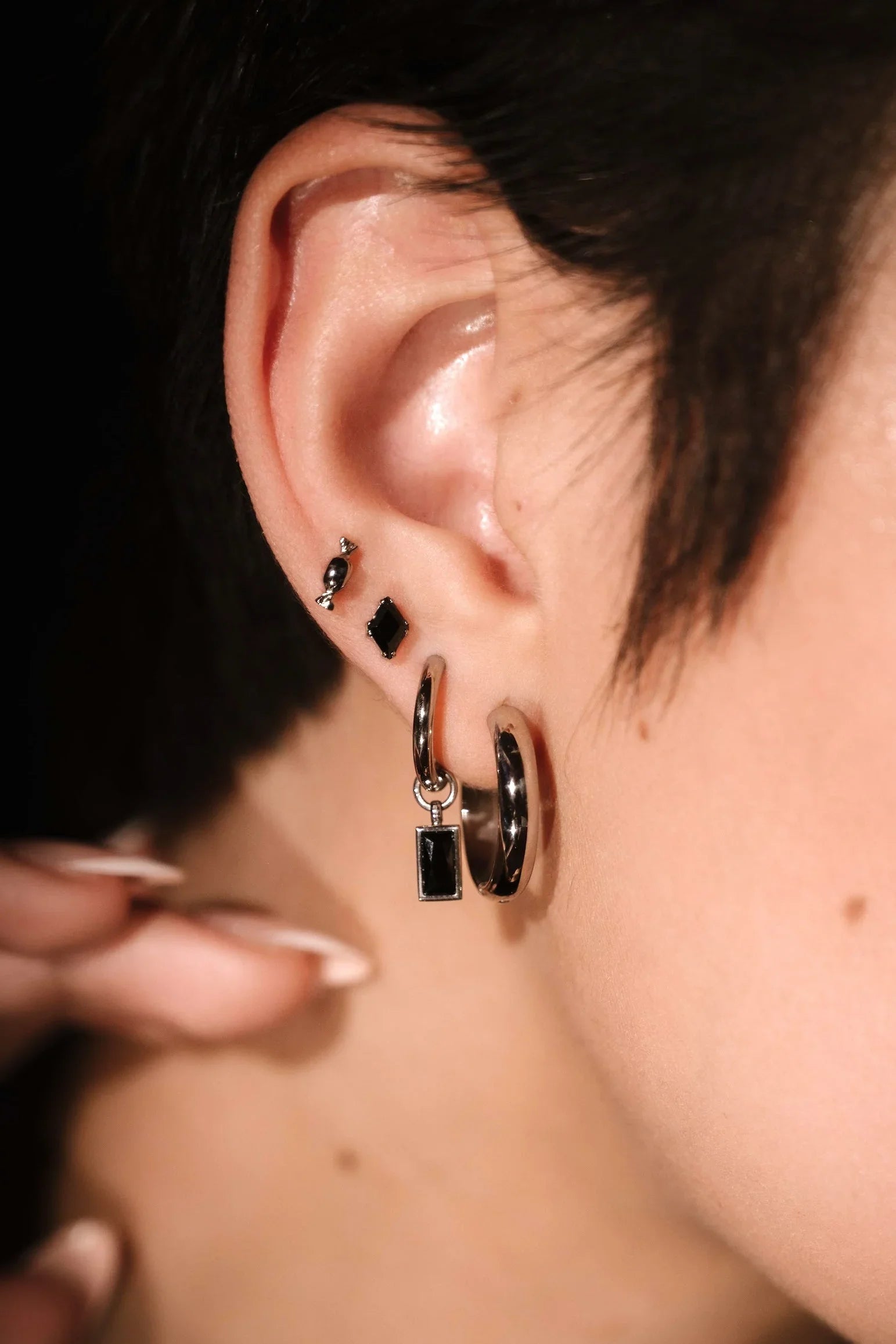 Close up of an ear wearing silver and black earrings