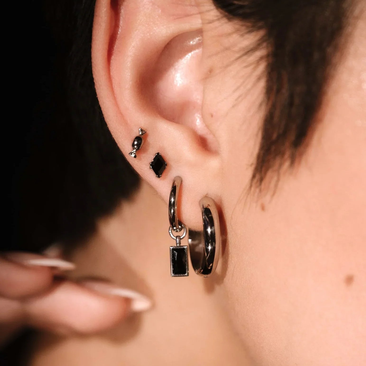 Close up of an ear wearing silver and black earrings