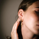Close-up of a person wearing gold hoop earrings with a neutral background