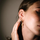 Close-up of a person wearing gold hoop earrings with a neutral background