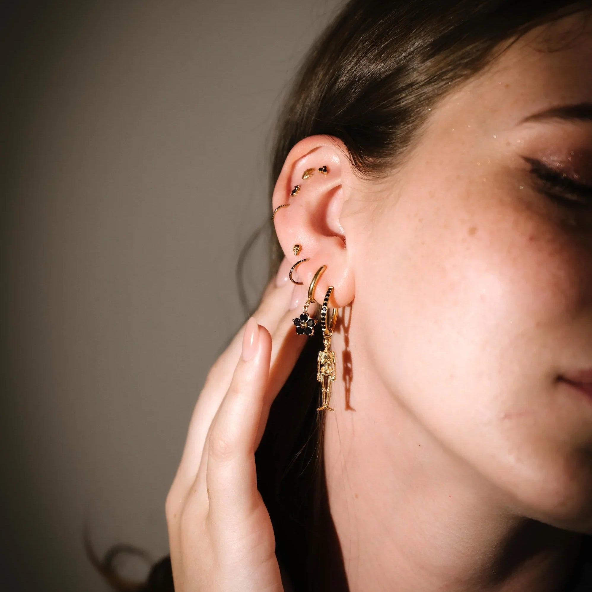 Close-up of a person wearing gold hoop earrings with a neutral background