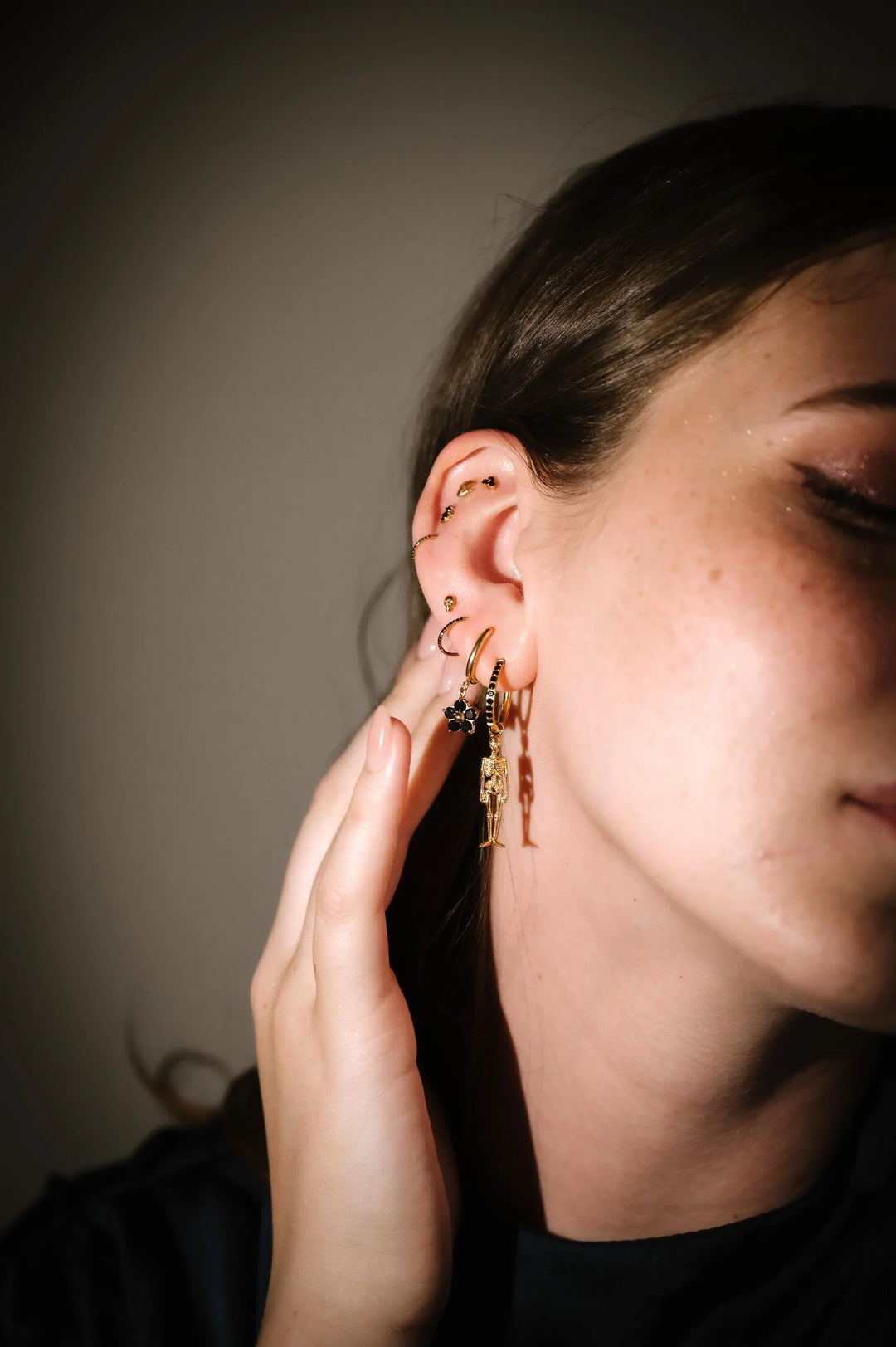 Close-up of a person wearing gold hoop earrings with a neutral background