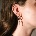 Gold and black earrings worn on an ear 