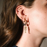 Gold and black earrings worn on an ear 