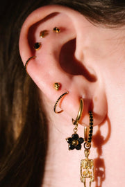 Close up photo of an ear wearing gold and black flat backs and hoops
