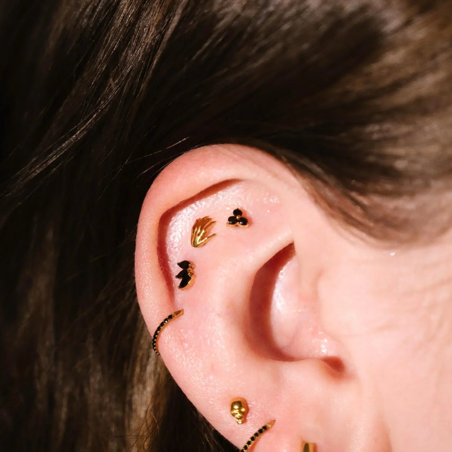 Close up of an ear with black and gold flat backs and hoops