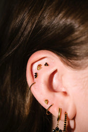 Close up of an ear with black and gold flat backs and hoops