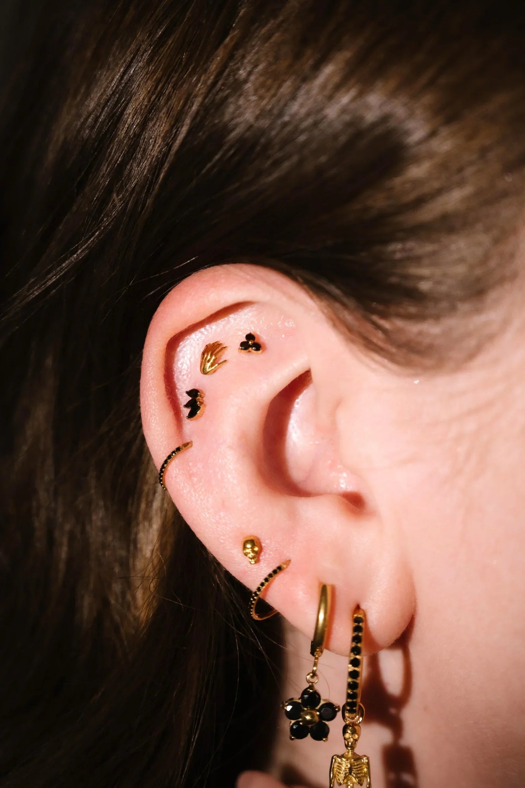 Close up of an ear with black and gold flat backs and hoops