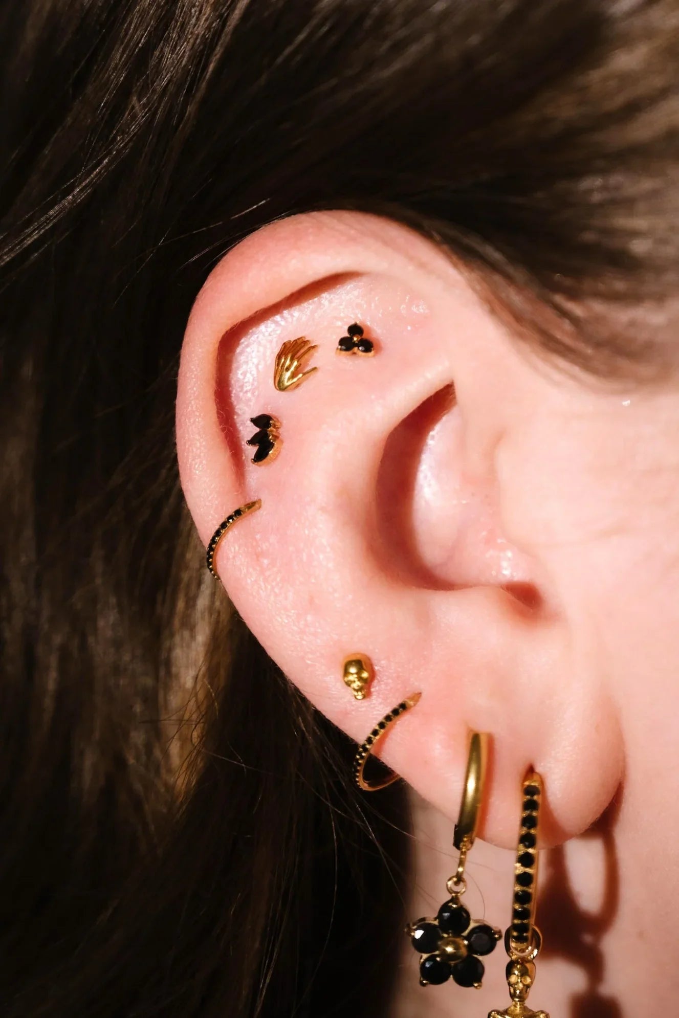 Close up of an ear with gold and black flat backs and hoops