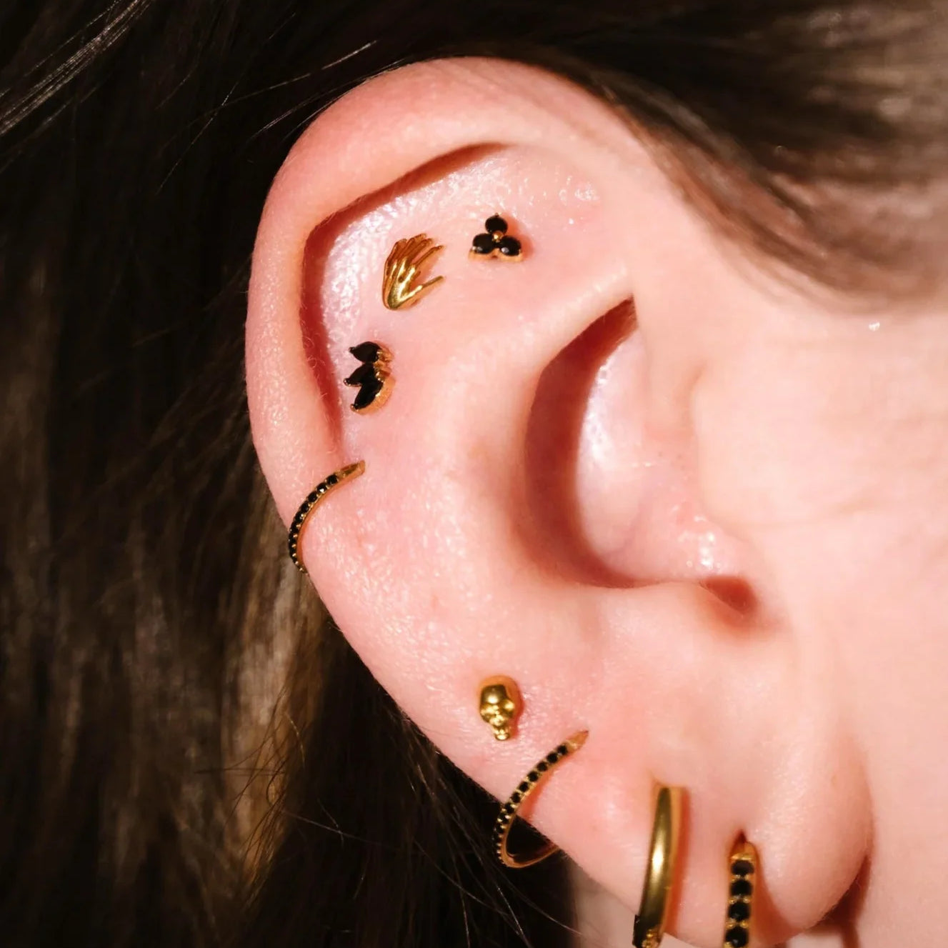 Close up of an ear with gold and black flat backs and hoops
