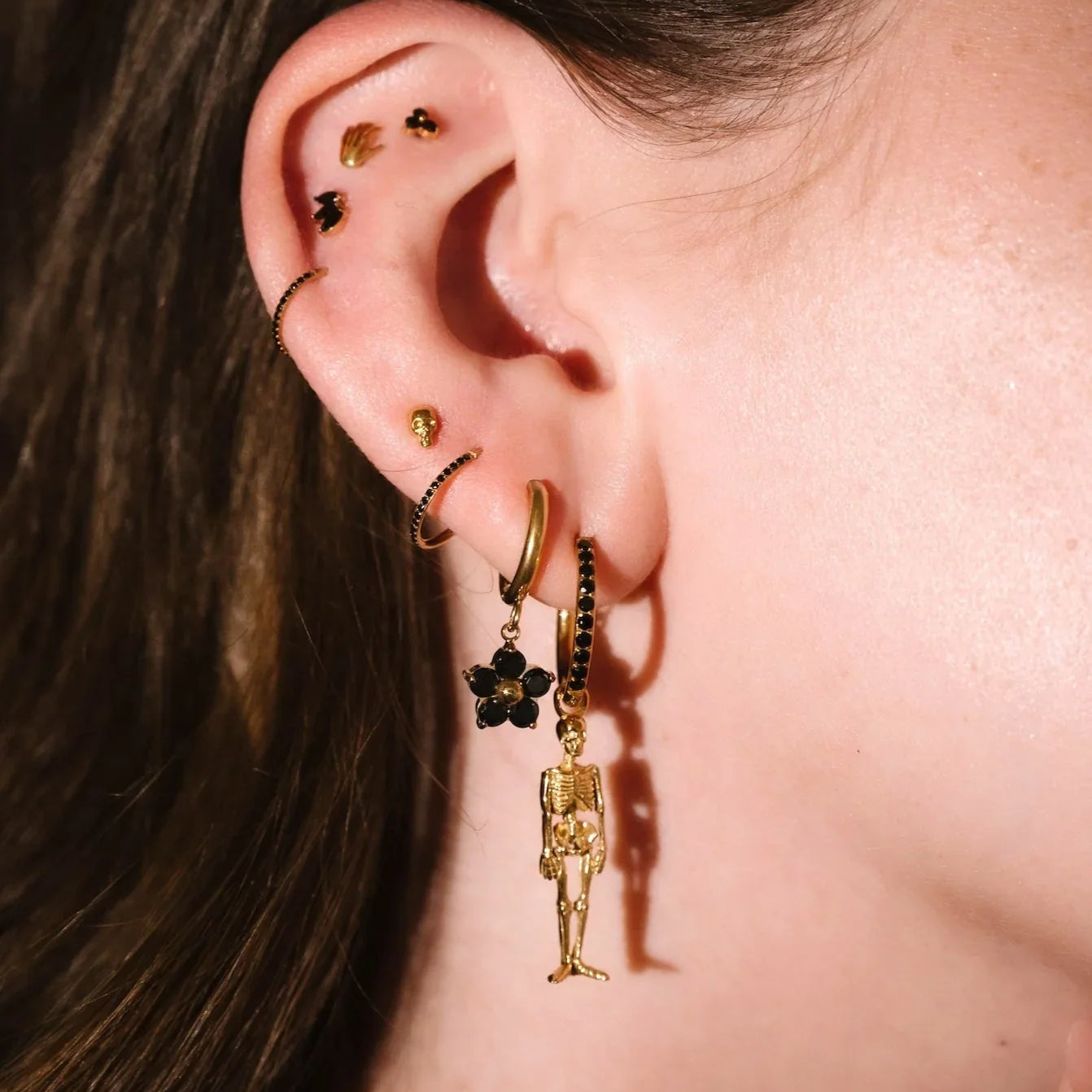 Gold and black earrings worn on an ear 
