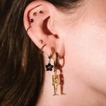 Gold and black earrings worn on an ear 