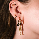 Gold and black earrings worn on an ear 