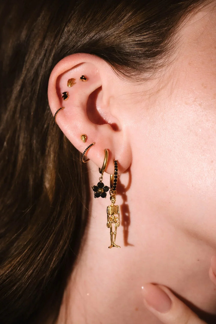Gold and black earrings worn on an ear 