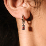 Close up of an ear with a hoop and garnet charm 