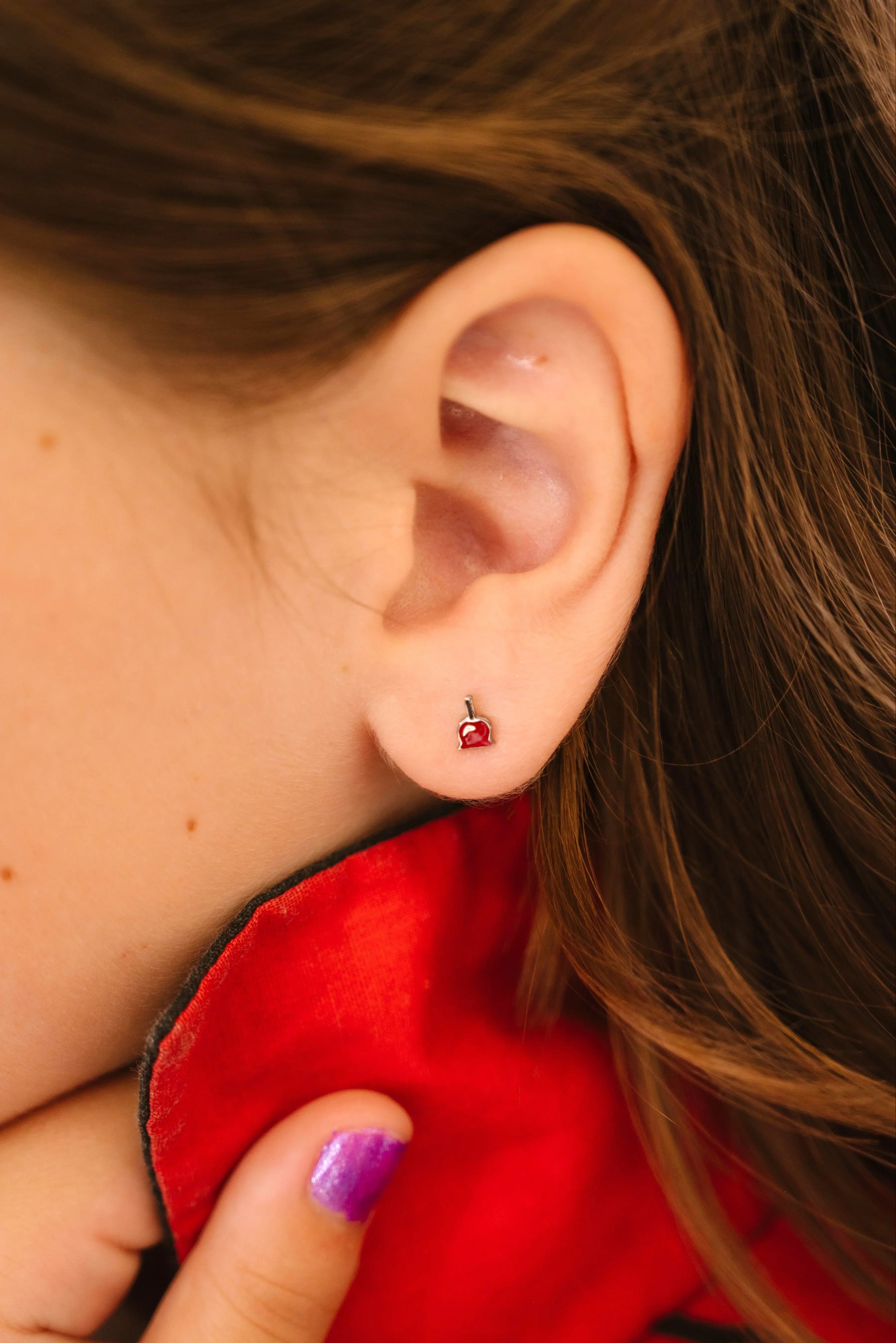 Close-up of a person wearing a red earring with a blurred background