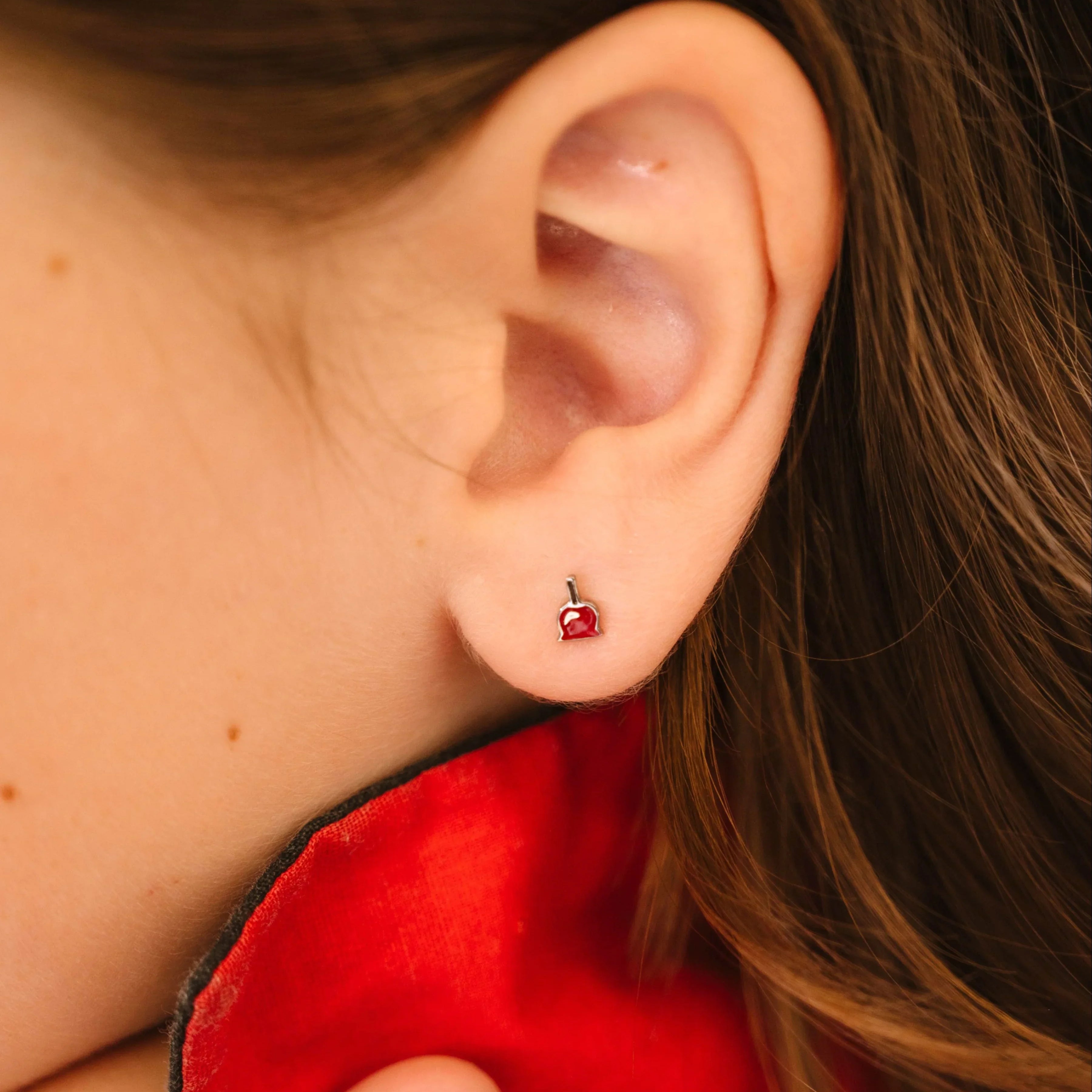 Close-up of a person wearing a red earring with a blurred background