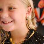 Girl with blonde hair wearing a black dress with gold accents, smiling.