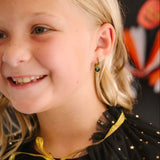 Girl with blonde hair wearing a black dress with gold accents, smiling.