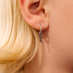 Close-up of an ear wearing a silver earring with blonde hair and blurred background