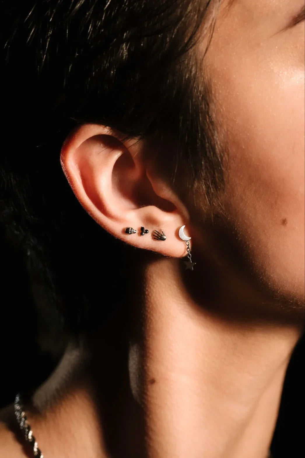 Close up of an ear with black and silver flat backs