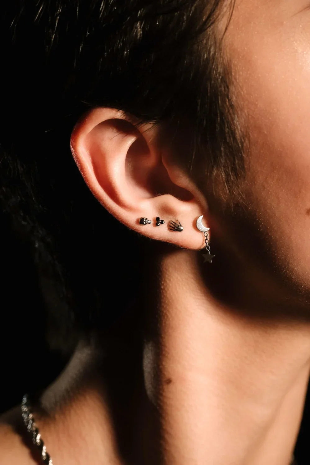 Close up of an ear with black and silver flat backs