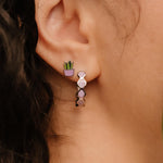Close-up of a person wearing a purple hoop earring with a blurred background
