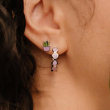 Close-up of a person wearing a purple hoop earring with a blurred background