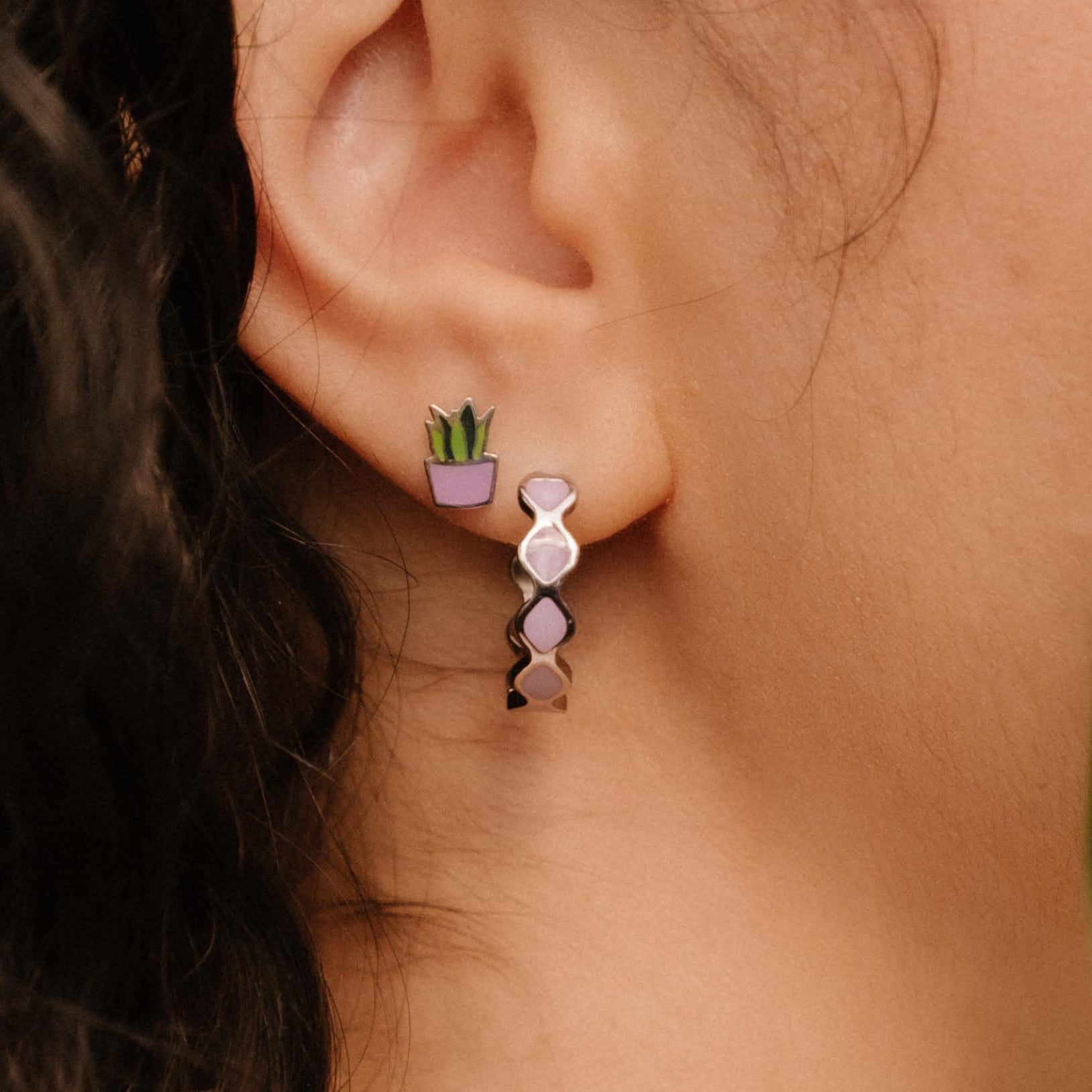 Close-up of a person wearing a purple hoop earring with a blurred background