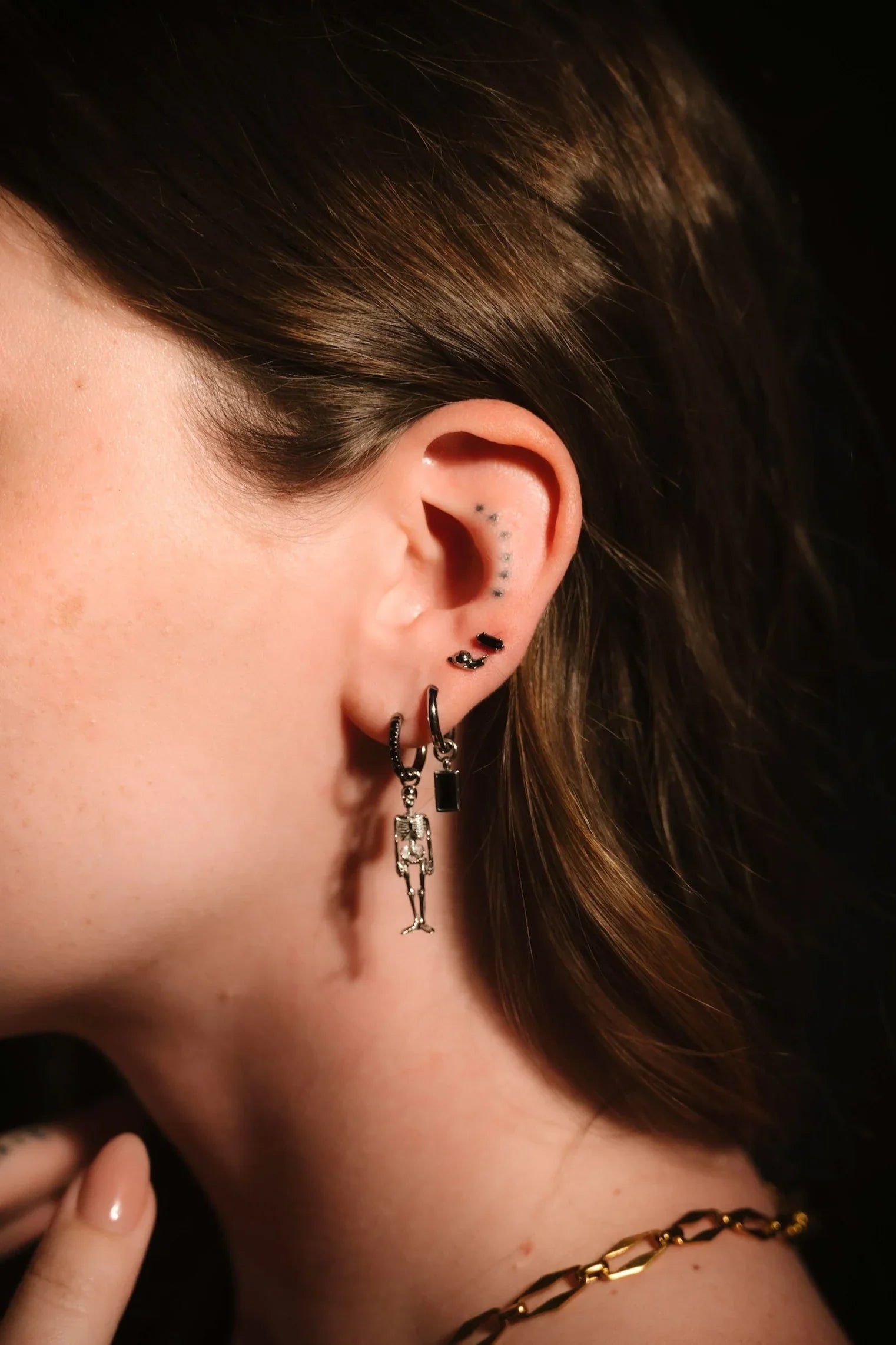 Close up photo of an ear wearing black and silver hoops and flat backs