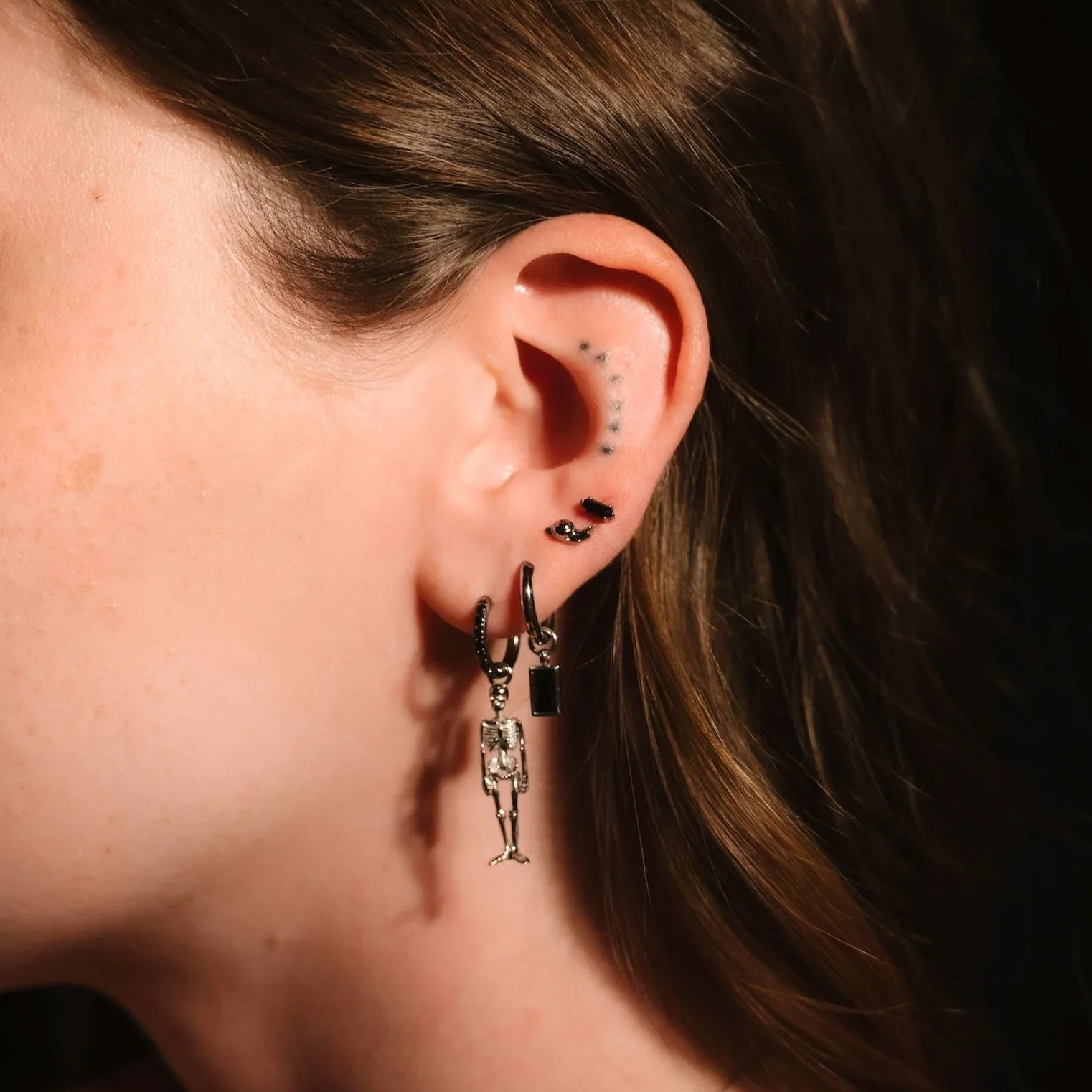 Close up photo of an ear wearing black and silver hoops and flat backs