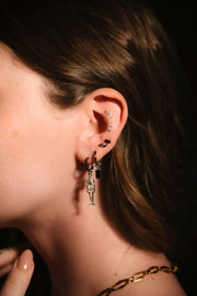 Close up photo of an ear wearing black and silver hoops and flat backs