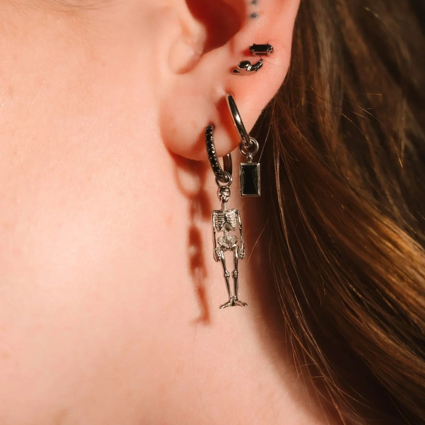 Close up of an ear with black and silver flat backs and hoops