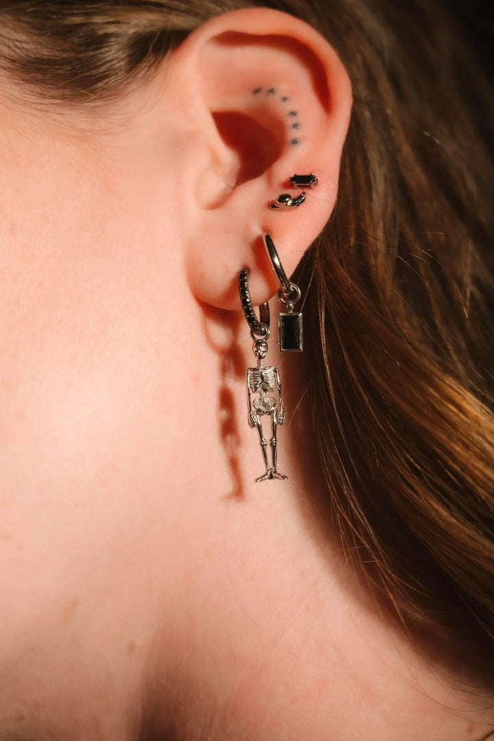 Close up of an ear with black and silver flat backs and hoops