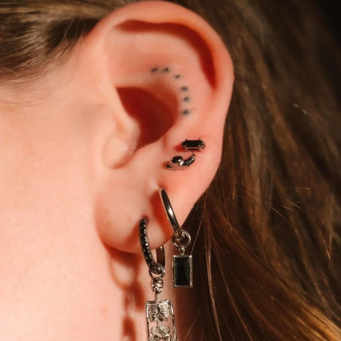 Black and silver earrings worn on an ear 