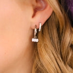 Close-up of a person wearing hoop earrings with 'BOO' charms.