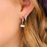 Close-up of a person wearing hoop earrings with 'BOO' charms.