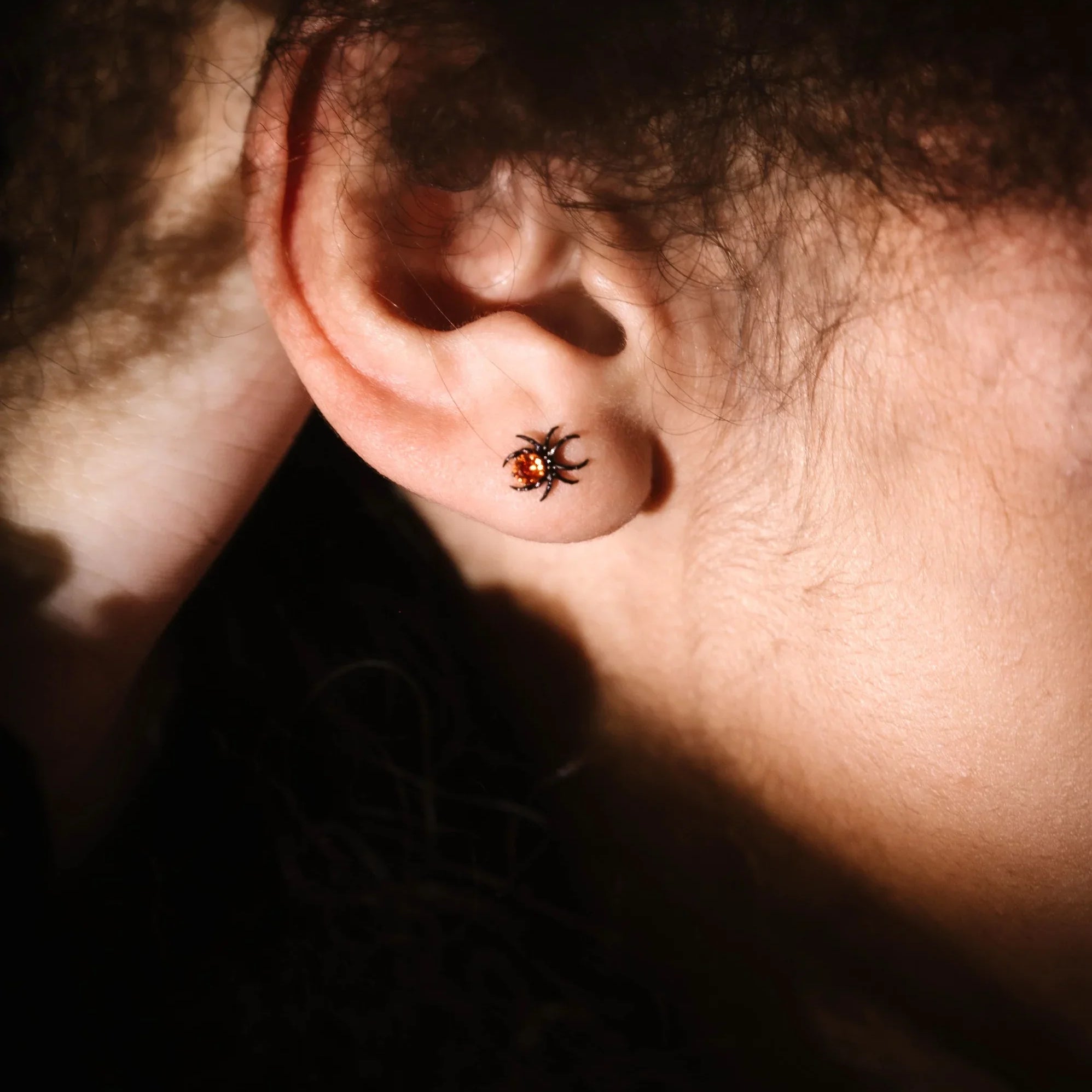close up photo of an ear wearing a spider flat back
