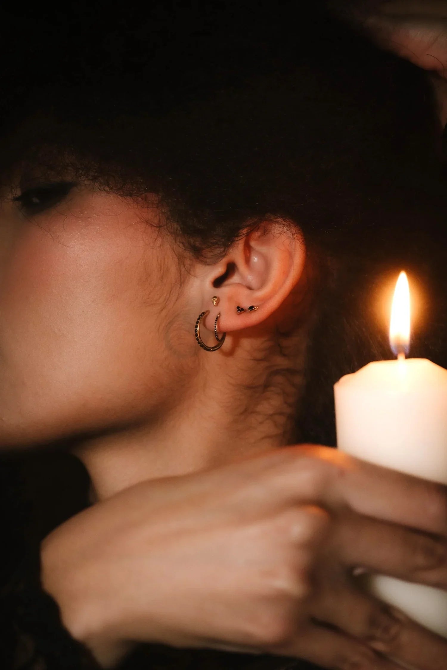 Close up photo of an ear wearing gold and black flat backs and hoops