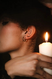 Close up photo of an ear wearing gold and black flat backs and hoops