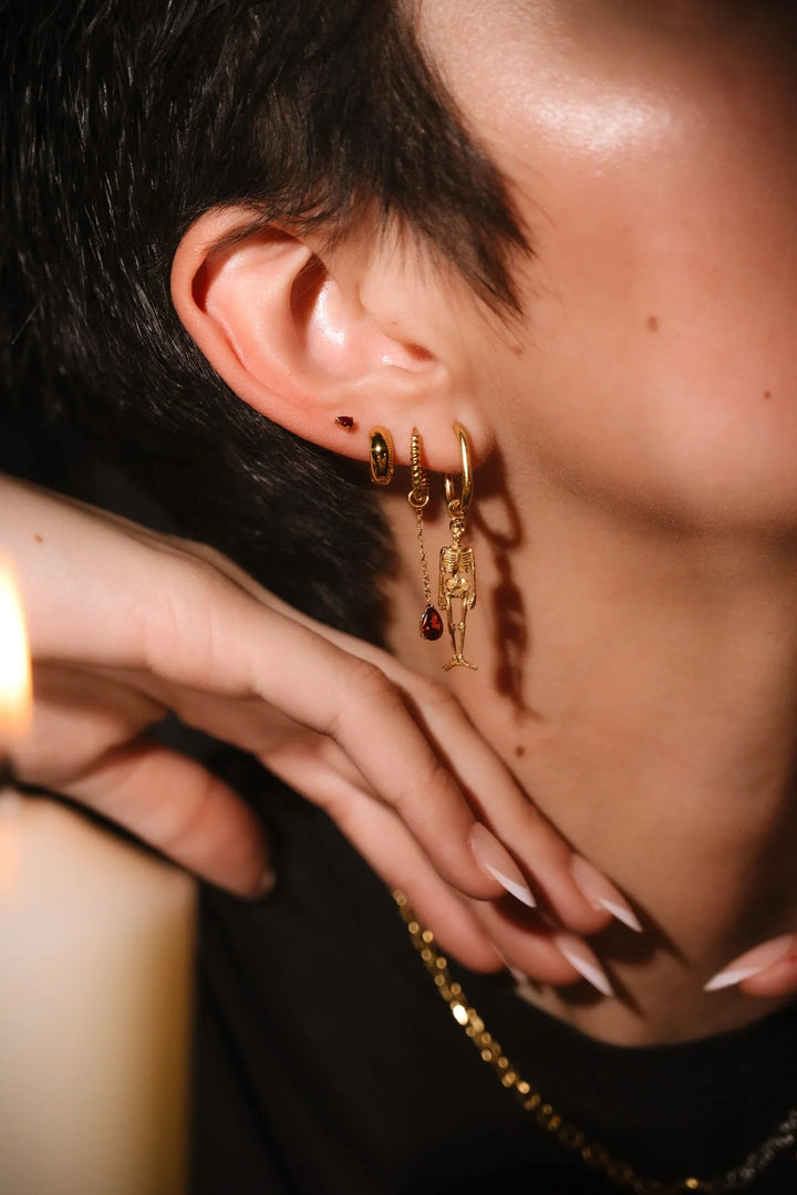 Close up of an ear with black and gold flat backs and hoops