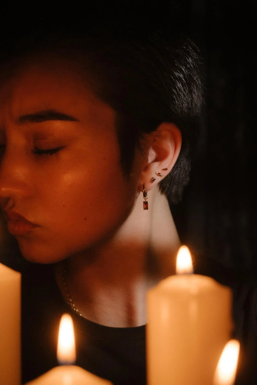 Profile shot of a model wearing garnet hoops and gold flat backs