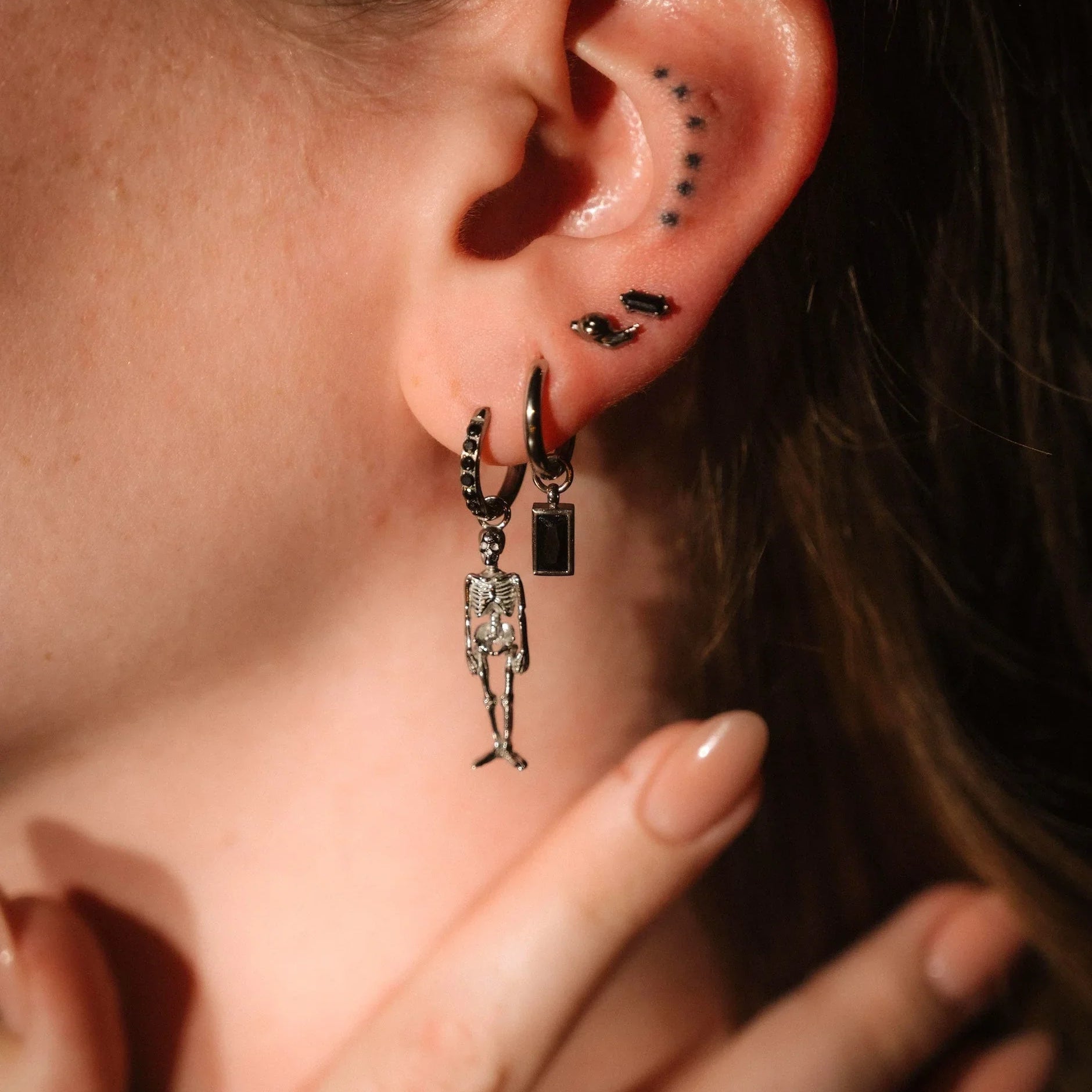 Close up of on ear wearing silver and black earrings