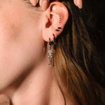 Close up of an ear with black and silver flat backs and hoops