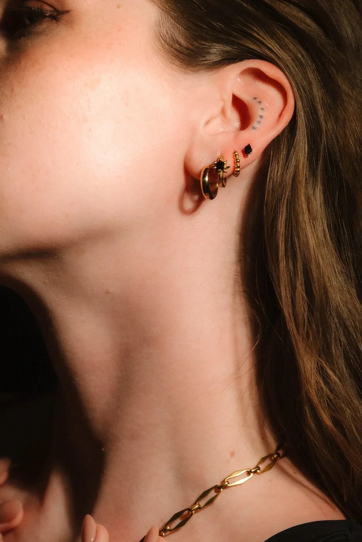 Profile headshot showcasing gold and black earrings